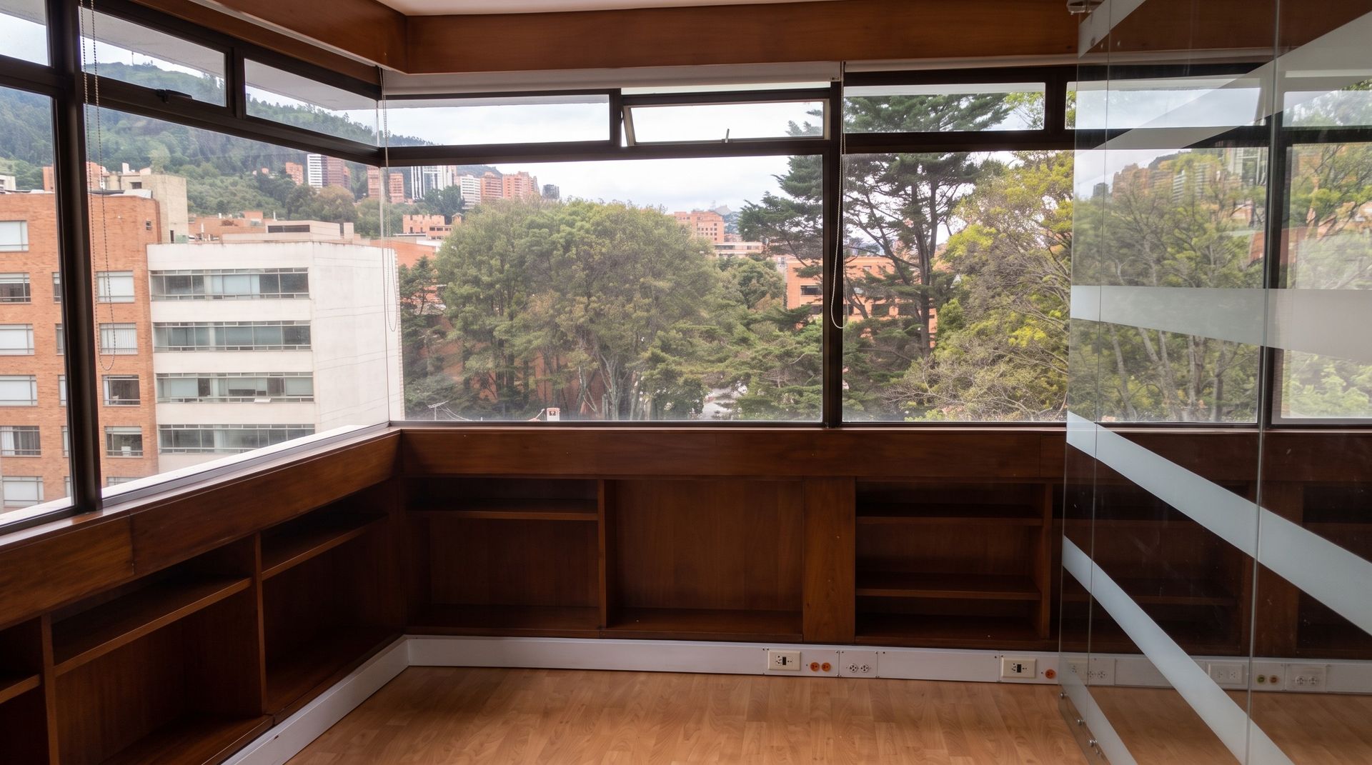 Oficina esquinera con mueble en madera bajo el ventanal